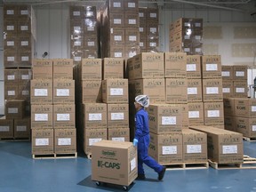 An employee is shown Monday stocking inventory at the CanadaCaps plant in Lakeshore.