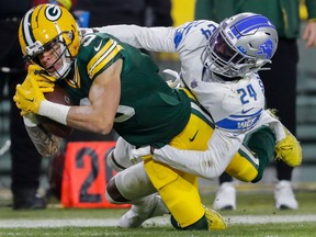 Green Bay Packers wide receiver Christian Watson is tackled by Detroit Lions cornerback Amani Oruwariye after making a reception at Lambeau Field.