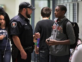 In this Oct. 7, 2015, file photo, a Windsor police constable chats with a student in the halls of Herman high school as part of a special program that designated an officer to patrolling high schools.