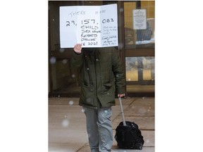 Jason Nassr leaves the London courthouse at lunch on Monday carrying a sign about sex abuse cases while supporters tried to block a news photographer. Nassr is on trial for harassment, extortion and producing and distributing child pornography related to a website that says it is hunting potential child predators. (Mike Hensen/The London Free Press)