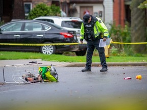 Windsor police officers with the accident reconstruction unit investigate at the intersection of Janette Avenue and Elliott Street West after a male was found with life-threatening injuries, on Friday, Oct. 15, 2021.