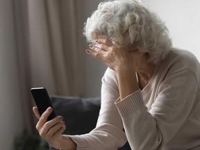 A senior-age woman reacts to her phone in this illustrative stock image.