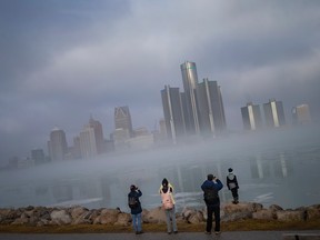 Une famille de quatre personnes tente de capturer le brouillard matinal qui se dissipe le long de la rivière Détroit, le lundi 2 janvier 2023.