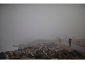 Un coureur s'hydrate en courant le long de la rivière Détroit dans le brouillard matinal, le lundi 2 janvier 2023.