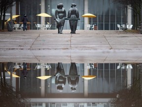 Large puddles from snow melt and rain cover Charles Clark Square as they reflect a promenade sculpture in front of city hall on Jan. 1, 2023.