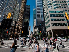 Pedestrians wearing masks walk across Front Street at Bay Street in Toronto during the COVID-19 pandemic, in 2020.