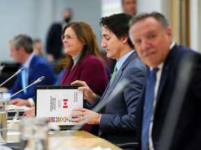 Prime Minister Justin Trudeau flips open a briefing book as he meets with Canada's premiers in Ottawa on Feb. 7 to discuss increased funding for health-care.