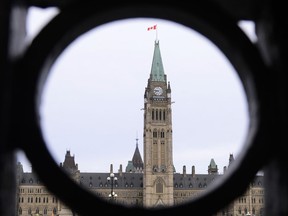 The Parliament Hill Peace Tower is framed in an iron fence on Wellington Street in Ottawa, March 12, 2020.