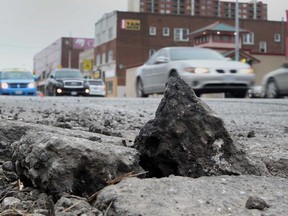 Broken asphalt on Wyandotte Street East at Pelissier Street in downtown Windsor. Photographed in March 2015.