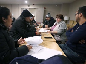 Patty Castro, second from right, a settlement worker with Matthew House Refugee Welcome Centre in Windsor helps refugee claimants with paperwork on Tuesday, March 14, 2023.