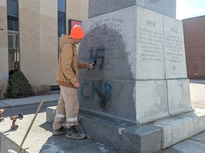 Adin Klaasen, with Memorial Restorations of Sarnia, works on trying to remove a swastika that was spray-painted on the cenotaph in downtown Chatham. (Handout)