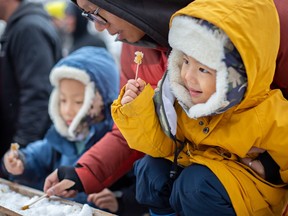 Isaac Ren, 3, is all smiles after dipping his snow stick in maple as he?s joined by his brother Jacob, 6, and father, Leon, at the March Maple Festival at John R. Park Homestead, on Sunday, March 12, 2023.