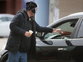 City council wants to crack down on aggressive panhandlers in Windsor. Here, a man panhandles at Ouellette Avenue and Wyandotte Street in downtown Windsor on Tuesday, March 28, 2023.