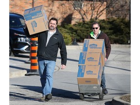 Ken Acton, left, and Craig Skoyles carry donations to a truck during the Tampon Tuesday event at the Harbour House in Windsor on Tuesday, March 7, 2023. The event was sponsored by the United Way.