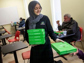 Aya Tarhuni, a student at Academie Ste. Cecile International School, hands out pizza at the Downtown Mission from money she raised to help feed the hungry during Ramadan, on Monday, April 17, 2023.