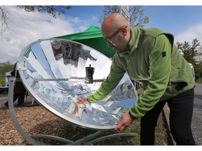 WINDSOR, ONT: APRIL 23, 2023. Juan David, a solar engineer with Green Sun Rising wipes rain drops off a concentrated solar cooker on display Sunday, April 23, 2023 at the Malden Park Earth day event.