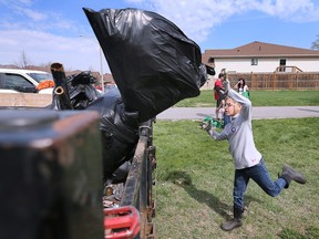 Aiden Winterburn, 10, heaves a bag a garbage  onto a trailer at the Little River Litter Cleanup event sponsored by ERCA on Saturday, April 15, 2023. He is a member of the Tecumseh 35th Cub Scouts.