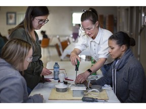 Erin Gouin, from Unifor, centre, helps WEST participants, from left, Samantha Tyre, Jocelyn Gilbert, and Jenny Lariviere, right, as they learn to wire a switch, light, and receptacle, during a trades exploration workshop at the Unifor office on Turner Road, on Monday, April 24, 2023.