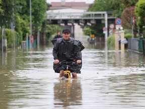 A man rides on a bicycle through floodwaters after heavy rains hit Italy's Emilia Romagna region.
