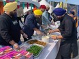 Bikramjit Singh of Windsor on the right loads up his plate with many of the food offerings at the Riverfront Plaza as part of the Khalsa Day celebrations on Sunday.