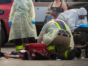 Opioid crisis. Paramedics and Windsor firefighters work on a male patient suspected of having overdosed from fentanyl on the pavement outside a service centre on the corner of Marentette Avenue and Tecumseh Road East on May 28, 2020.