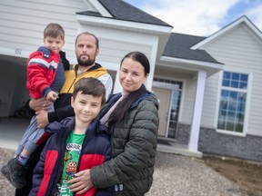 The Romanyuk family — Nikolai and his wife Irena, with their sons, Max, 6, left, and Nazar, 9 — are shown outside their new home on Belleview Drive in Cottam, on Sunday, April 30, 2023.