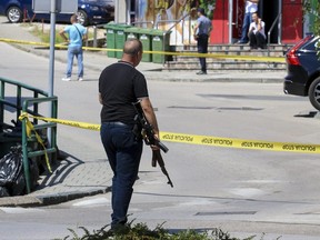 A plain-clothes police officer holds a rifle as they launch a major chase for a man who claimed to have shot and killed his wife while broadcasting it live on Instagram, in the small town of Gradacac, Bosnia, Friday, Aug. 11, 2023.