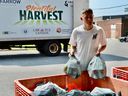 High school student Alex Hall gathers bags of food for people accessing the UHC — Hub of Opportunities walk-up/drive-thru emergency food bank on Thursday, Aug. 3, 2023, in the parking lot of the Adie Knox Herman Recreation Complex on Windsor's west side.
