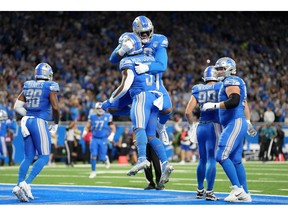 Running back David Montgomery (No. 5) and offensive tackle Penei Sewell (No. 58) celebrate after Montgomery scored a touchdown in the first quarter against the Carolina Panthers at Ford Field on Sunday.