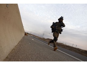 An Israeli soldier runs for cover on a road during combat with Hamas soldiers near Sderot, Israel.
