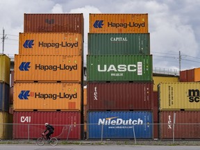 The federal government has announced an investment of up to $150 million to build a new container terminal in Contrecoeur, Quebec, which is about 70 kilometres northeast of Montreal. A cyclist passes shipping containers at a transloading and container storage facility in Montreal, Friday, June 9, 2023.