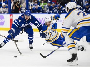 Maple Leafs’ Auston Matthews fights off Sabres’ Connor Clifton (75) and defenceman Owen Power at Scotiabank Arena last night.