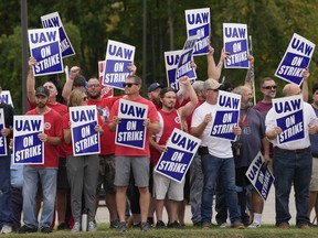 FILE - United Auto Workers members hold picket signs near a General Motors assembly plant in Delta Township, Mich., Sept. 29, 2023. About 46,000 United Auto Workers at GM are expected to wrap up voting on a tentative contract agreement in a close race that will decide the fate of the deal that ended a six-week strike. The union is expected to announce GM results Thursday evening.