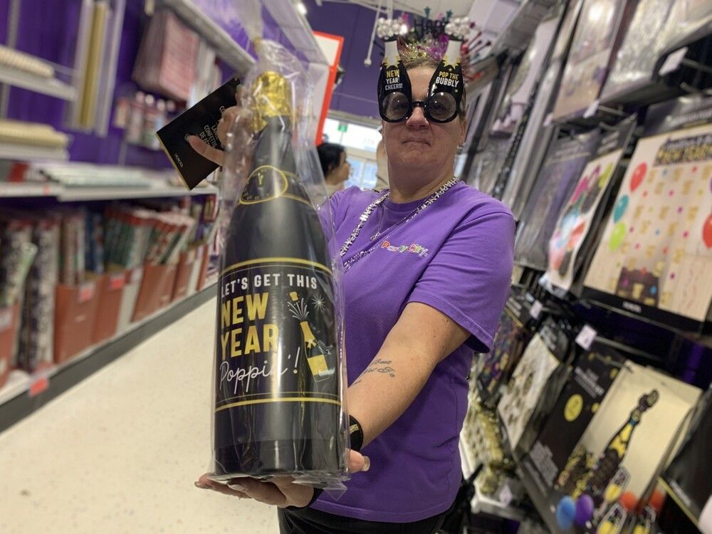 La empleada de Party City, Kim Murphy, muestra algunos de los artículos de fiesta que se ofrecen en la tienda para los juerguistas de Nochevieja.