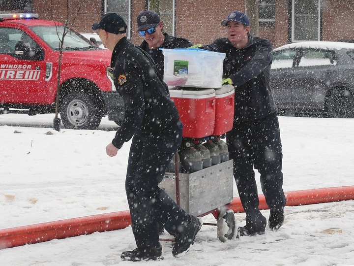  Windsor firefighters push a cart of supplies through snow at a townhouse fire on Tuesday, January 30, 2024 in the 6300 block of Thornberry Crescent.