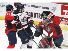 Windsor native and new Spitfires goaltender Max Donoso juggles the puck while teammate Anthony Cristoforo, left, tangles with Saginaw Spirit forward Ethan Hay during Wednesday's game.