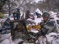 EDMONTON, CANADA - JANUARY 9, 2024: A determined group of First Nations residents stands resolute, adamantly refusing to leave, as police and city crews prepare to clear the last of eight high-risk homeless encampments marked for removal, on January 9, 2024, in Edmonton, Alberta, Canada. Central Edmonton's homeless encampment resisted removal as residents, supported by an advocacy group citing a court order breach, stood their ground. The standoff, marked by heavy snowfall, underscored concerns over shelter safety and revealed strained relations between city officials, police, and advocates for justice and human rights.