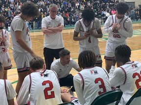 Holy Names Knights head coach Ryan Steer, centre, goes over strategy with his players.