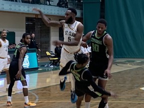 St. Clair Saints' forward Chad Vincent-Simon (5) dishes off the ball after colliding with Centennial Colts' Crawford Tayeshaun during Saturday's OCAA men's basketball quarter-final game at the St. Clair College SportsPlex.