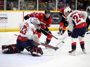 Owen Sound Attack forward Servac Petrovsky looks to split Windsor Spitfires' goaltender Joey Costanzo and defenceman Carson Woodall while tracking down a rebound during Saturday's game.