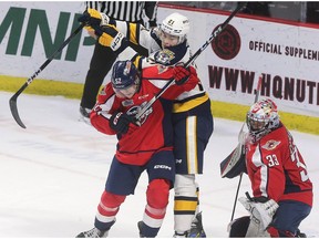 Windsor Spitfires' defenceman Connor Toms, left, tangles with Erie Otters' forward Alex Messier in front of Winsor goalie Joey Costanzo during Thursday's game. of the Erie Otters tangle in front of goalie Joey Costanzo during Thursday's game.