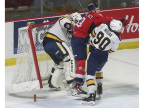 Windsor Spitfires' forward A.J. Spellacy, centre, gets sandwiched between Erie Otters' goalie Ethan Fraser and Martin Misiak on Thursday.