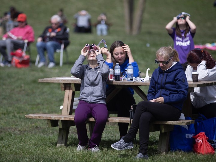  A young person gazes at the sun through eclipse glasses and binoculars as the moon begins to eclipse the sun at Mettawas Park in Kingsville on Monday, April 8, 2024.