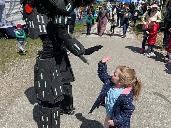  Elizabeth Adams high-fives Optimus the robot during Earth Day activities at Malden Park in Windsor on Sunday, April 21, 2024.