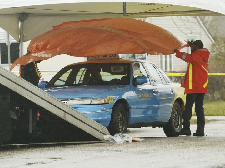  Ahead of being towed away from a crime scene in Windsor on Nov. 19, 2004, the taxi in which a cabbie was found murdered in the back seat is covered up on Montrose Avenue.