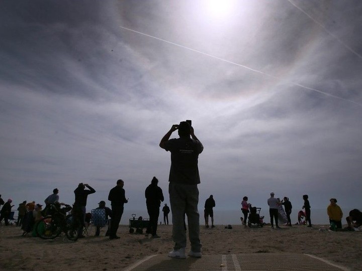  People take in the solar eclipse on Monday, April 8, 2024, at Seacliff Beach in Leamington.