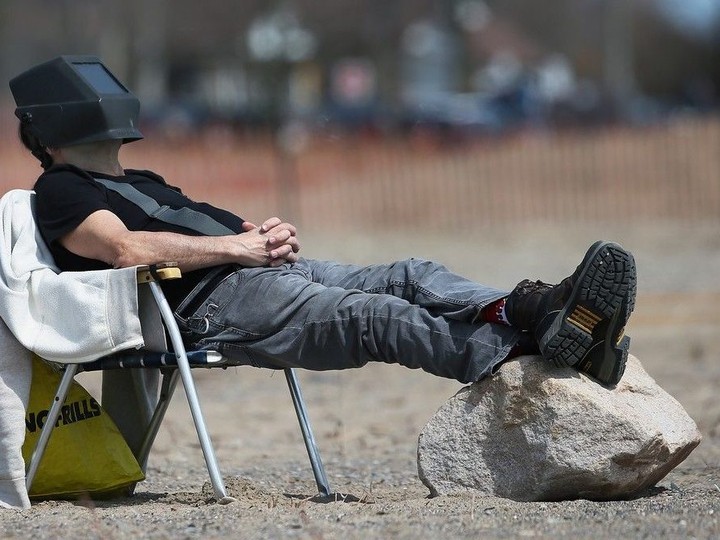  A man uses a welder’s mask to watch the solar eclipse on Monday, April 8, 2024 at the Seacliff Beach in Leamington.