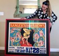 Meredith Smith is shown with a framed circus poster after restoration. (Supplied)