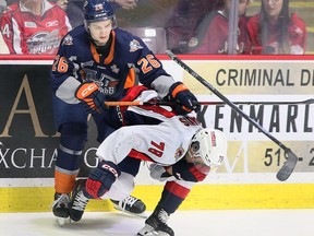 El defensa de los Windsor Spitfires, Tanner Winegard, izquierda, lucha con el delantero de los Flint Firebirds, Matthew Wang, frente al portero de los Windsor, Joey Costanzo, durante el partido del martes en el Centro WFCU.