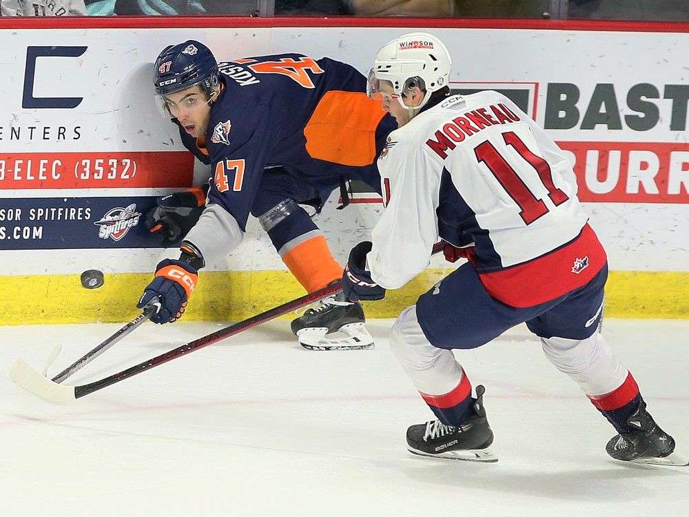 El defensa de los Windsor Spitfires, Tanner Winegard, izquierda, lucha con el delantero de los Flint Firebirds, Matthew Wang, frente al portero de los Windsor, Joey Costanzo, durante el partido del martes en el Centro WFCU.